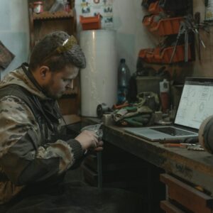 Man in Brown Camouflage Jacket Sitting on Chair Holding a Tool